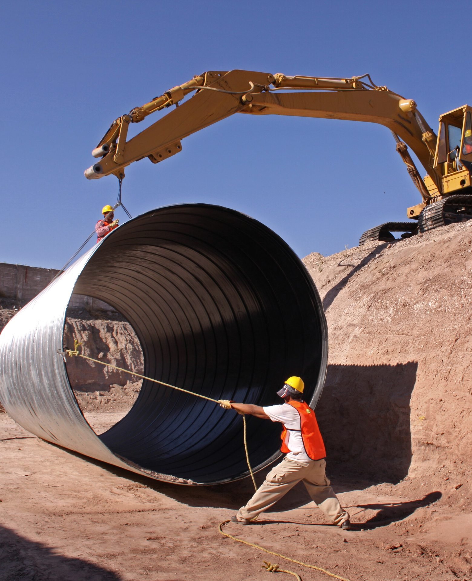 Crew setting a large culvert pipe with an excavator